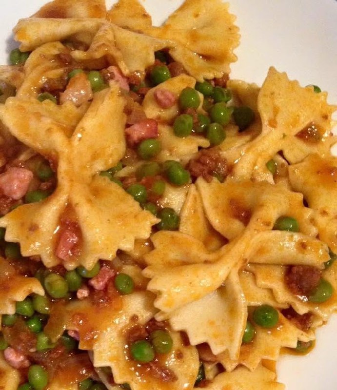 Farfalle fresche fatte in casa con piselli, pancetta croccante e pomodorini dolci